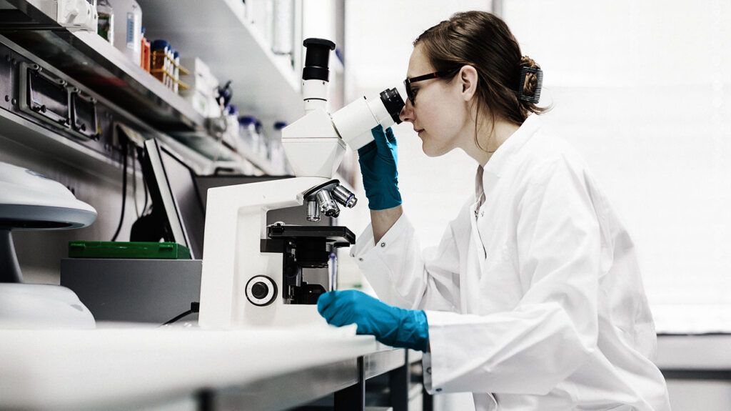 girl in lab looking through microscope